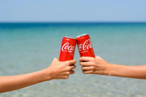 Two cans of Coca-Cola in the hands of friends against the background of the sea. Stock-Fotos