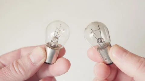 Two car bulbs in hands: one intact, the other burnt out Stock Footage 306613069