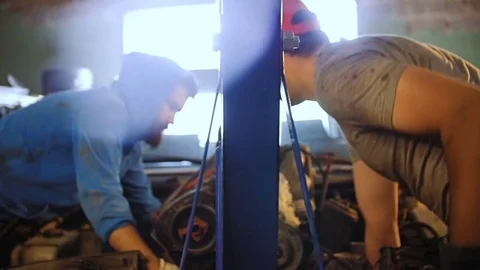 Two car mechanic with a mini crane pull out of the car motor. Stock Footage 77175538
