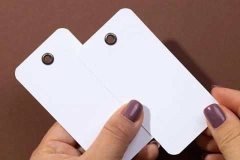 Two cardboard white blank rectangular tags with small holes in upper part for Stock Photos