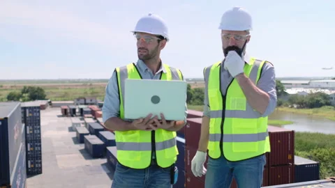 Two cargo container workers discuss and work together that they stand over top Stock Footage 146429950
