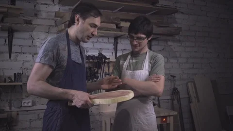 Two carpenter masters discuss a piece of wood (round timber) in the workshop Stock Footage 102567782