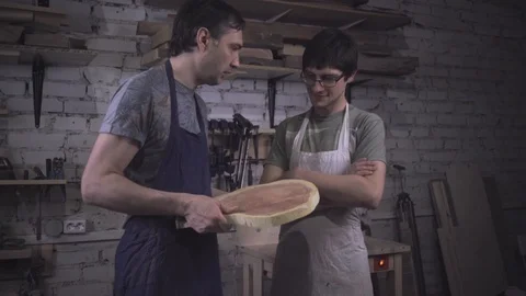 Two carpenter masters discuss a piece of wood (round timber) in the workshop Stock Footage 102567785