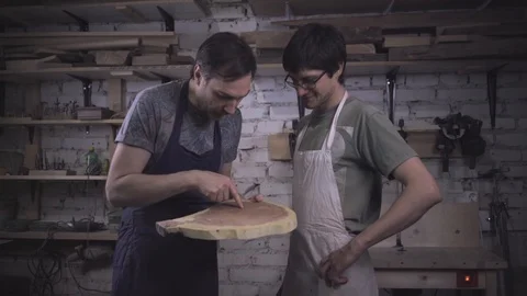 Two carpenter masters discuss a piece of wood (round timber) in the workshop Stock Footage 102567832