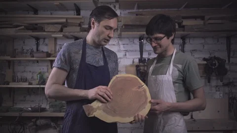 Two carpenter masters discuss a piece of wood (round timber) in the workshop Stock Footage 102567898