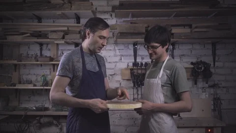Two carpenter masters discuss a piece of wood (round timber) in the workshop Stock Footage 102567899
