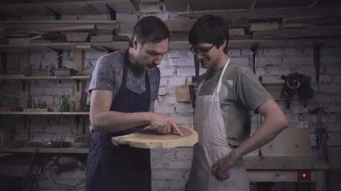 Two carpenter masters discuss a piece of wood (round timber) in the workshop Stock Footage 102567900