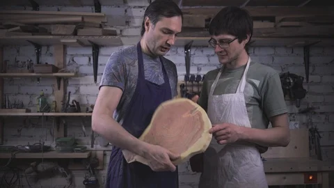 Two carpenter masters discuss a piece of wood (round timber) in the workshop Stock Footage 102567958