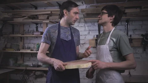 Two carpenter masters discuss a piece of wood (round timber) in the workshop Stock Footage 102567978