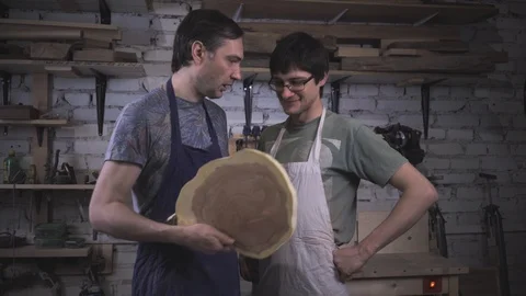 Two carpenter masters discuss a piece of wood (round timber) in the workshop Stock Footage 102568030