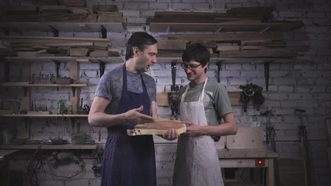 Two carpenter masters discuss a piece of wood (round timber) in the workshop Stock Footage 102568045
