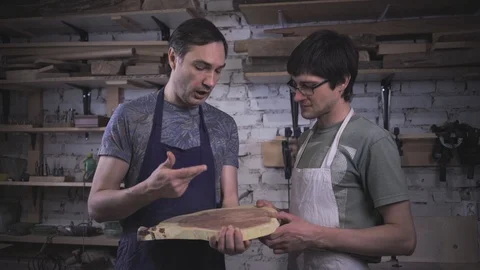 Two carpenter masters discuss a piece of wood (round timber) in the workshop Stock Footage 102568066