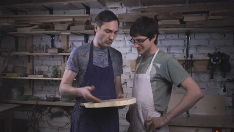 Two carpenter masters discuss a piece of wood (round timber) in the workshop Stock Footage 102568121