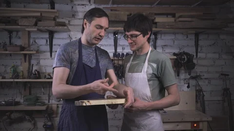 Two carpenter masters discuss a piece of wood (round timber) in the workshop Stock Footage 102568133