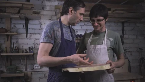 Two carpenter masters discuss a piece of wood (round timber) in the workshop Stock Footage 102568149