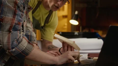 Two Carpenters Discussing Blueprint Using Laptop in Workshop Stock Footage 340394296