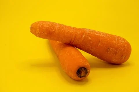 Two carrots on a yellow background. Stock Photos