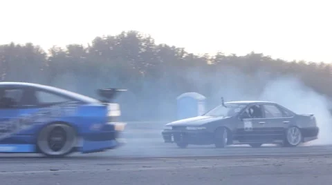 Two cars drift side by side around a corner on closed race track. Stock-Footage 59762223