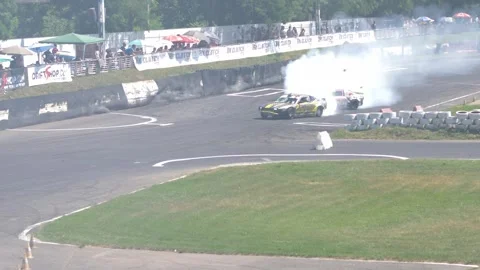 Two cars drifting side by side with lots of smoke and burned tires. Stock Footage 246554008