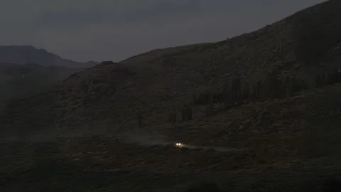 Two Cars with Headlights Illuminating Remote Mountain Landscape at Night Video stock 336563645
