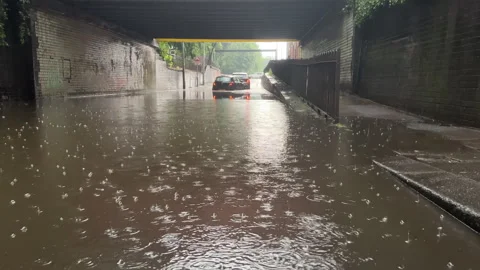 Two cars stranded under bridge in torrential rain, warning lights flashing. Stock Footage 307341737
