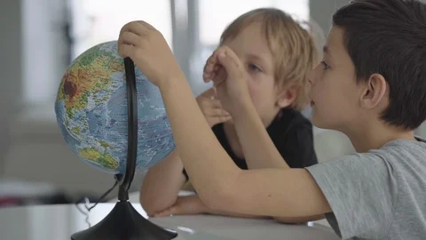 Two caucasian boys spin a globe and dream about travel. Видео 91585807
