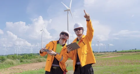 Two caucasian engineers in orange uniform control drone flight and check turbine Stock Footage 325845135