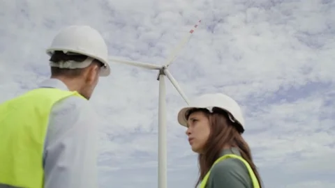Two caucasian engineers standing on wind turbine field Stockbeeldmateriaal 221223513