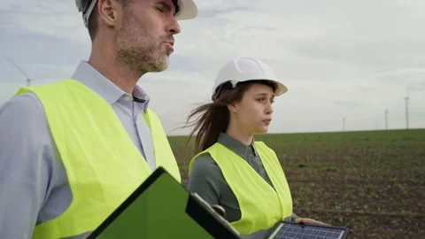 Two caucasian engineers walking on wind turbine field and discussing Stock-Footage 221223902