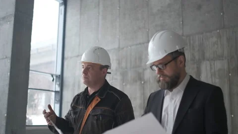 Two Caucasian Handsome Men In Helmets Talking And Looking At The Big Paper With Stock Footage 106870415