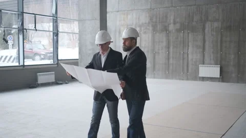 Two Caucasian Handsome Men In Helmets Talking And Looking At The Big Paper With Video stock 106991380
