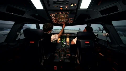 Two caucasian male pilots in the cockpit or flight deck of a passenger airplane Stock Footage