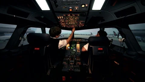 Two caucasian male pilots in the cockpit or flight deck of a passenger airplane Stock Footage 77333992