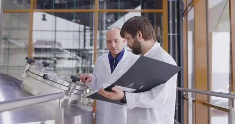 Two Caucasian mans working at a brewery factory. A male brewer checks the Stock-Footage 147950279