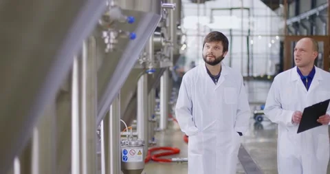 Two Caucasian mans working at a brewery factory. A male brewer checks the Vídeos de archivo 147950586
