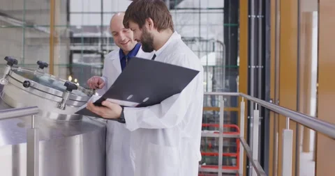 Two Caucasian mans working at a brewery factory. A male brewer checks the Video stock 148123436