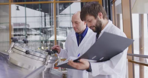 Two Caucasian mans working at a brewery factory. A male brewer checks the Video stock 148391227