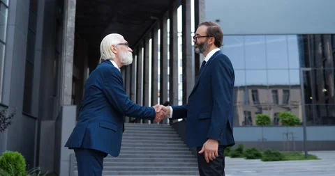Two Caucasian men shaking hands outdoors at business center when meet at street Stock Footage 148245175