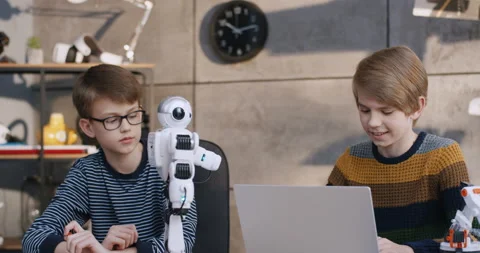 Two Caucasian nice and smart teen schoolboys exploring a toy robot functions 動画素材 135842700