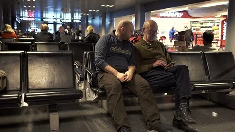 Two caucasian type men talking in the airport lounge Stock Footage 83495095