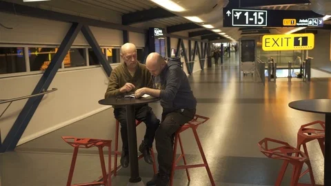 Two caucasian type men talking in the airport cafe Stock Footage 83495462