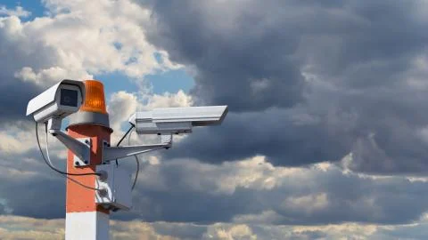 Two CCTV security cameras on red striped pillar with orange flashing light ag Stock Photos