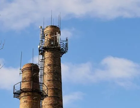 Two cell tower above cellular base station. Brick chimneys of boiler building Stock Photos