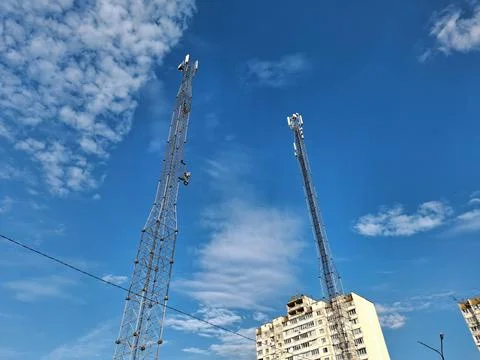 Two cell towers on blue background near residential area Stock Photos