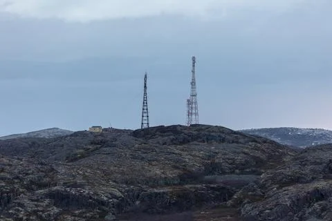 Two cell towers stand on a rugged, moss-covered tundra hill next to a small Stock Photos