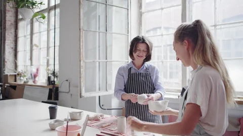 Two ceramic artists talking cheerfully in art studio Stock Footage 106832412