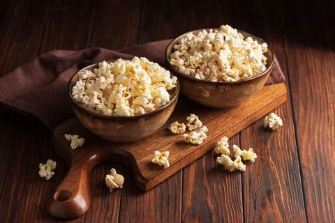 Two ceramic bowls filled with fluffy popcorn on rustic wooden background pe.. Stock Photos