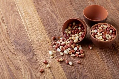 Two ceramic bowls with raw peanuts mix isolated over rustic wooden backround Stock Photos