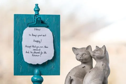 Two ceramic cats sit next to a memory board with a handwritten reminder about Foto stock