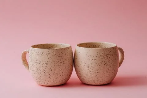 Two ceramic cups stand on a pink background, copy space Stock Photos